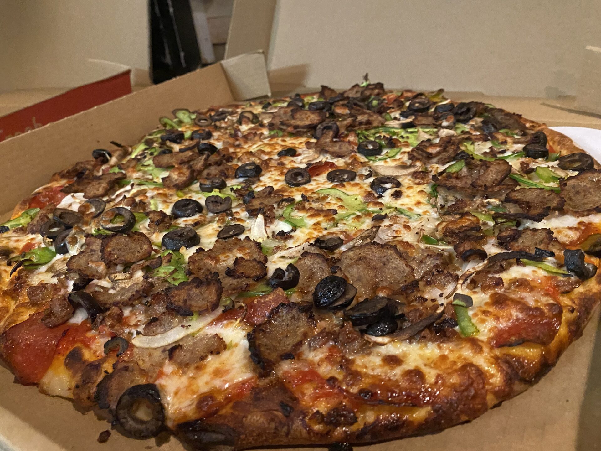 A pizza sitting on top of a box covered in toppings.